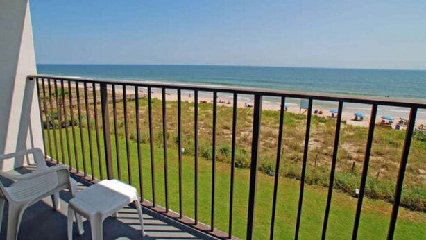 A balcony with a view of the beach and ocean.
