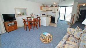 A compact living space with a kitchenette, a dining area, a television, and a sofa.