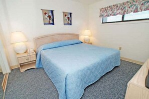 Ein Schlafzimmer mit einem Bett, zwei Nachttischen mit Lampen und zwei an der Wand hängenden Bildern.