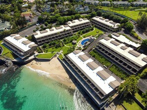 Ein Küstenresort mit mehreren Gebäuden, einem Strand und einem Schwimmbad.