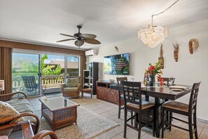 Ein geräumiges Wohnzimmer mit Essbereich, Deckenventilator, Flachbildfernseher und Balkon mit Aussicht.