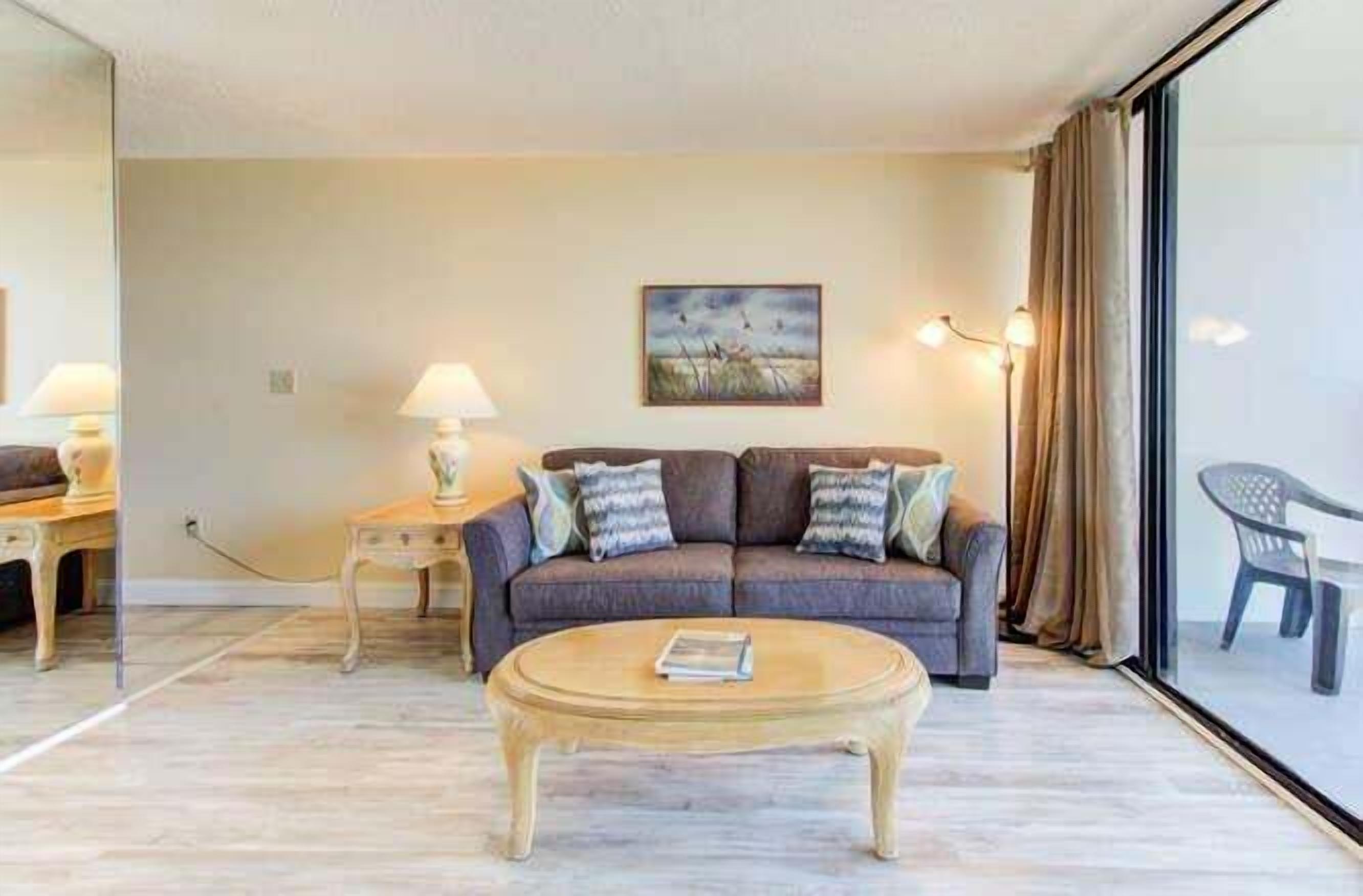 A living room with a sofa, a coffee table, a lamp, and a painting on the wall.