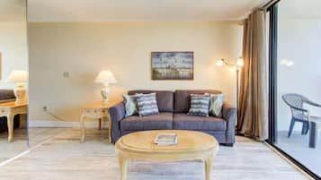 A living room with a sofa, a coffee table, a lamp, and a painting on the wall.