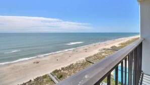 En balkon med udsigt over strand og hav.