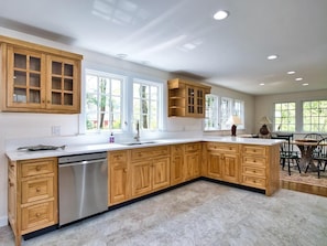 A spacious kitchen with wooden cabinets, a dishwasher, and a large island.