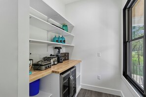A compact kitchenette with a built-in oven, a coffee maker, and storage shelves. - Experience luxury at Summit and Shore, a 5-bedroom retreat in beautiful Swanton, MD. (Swanton)