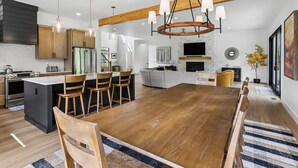 Una cocina moderna con una isla central, sillas de madera e iluminación colgante.