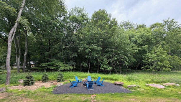 Un área de picnic con sillas Adirondack azules, una mesa central y un camino de piedra que la conduce.