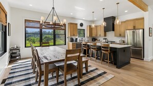 Una cocina moderna con armarios de madera, un refrigerador de acero inoxidable y una isla grande con taburetes de bar.