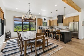 Eine moderne Küche mit Holzsärchen, einem Edelstahlkühlschrank und einer großen Kochinsel mit Barhocker.