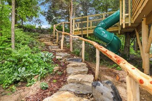 A wooden staircase with a green slide leading to a wooden platform.