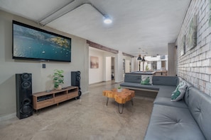 A living room with a large TV, a sofa, a coffee table, and a speaker system. - Encanto House in Provenza by Nowa (Medellín)