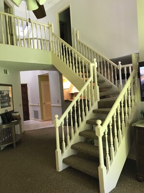 Eine Treppe mit weißen Balustraden und Teppichstufen, die zu einer oberen Ebene führt.