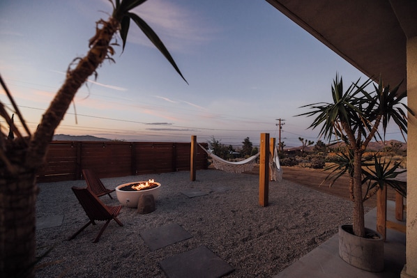 Eine Terrasse mit Feuerstelle, Sitzgelegenheiten und einer Hängematte.