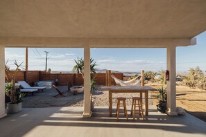 An outdoor patio with a table and chairs, lounge chairs, and potted plants. - Romantic Desert Oasis, Hot Tub, Stargazing, 10 Min to JTNP! (Joshua Tree)