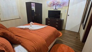 Ein Schlafzimmer mit Bett, Kommode, Fernseher und Tür.