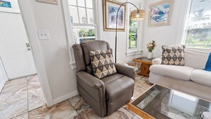 A living room with a brown leather recliner, a white sofa, a glass coffee table, and a floor with patterned tiles. - NEW: Cozy Home w/ Hot tub & Beach Essentials! (Lake Worth Beach)