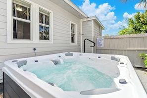 Ein Whirlpool vor einem Haus mit Holzzaun und einem Schild.