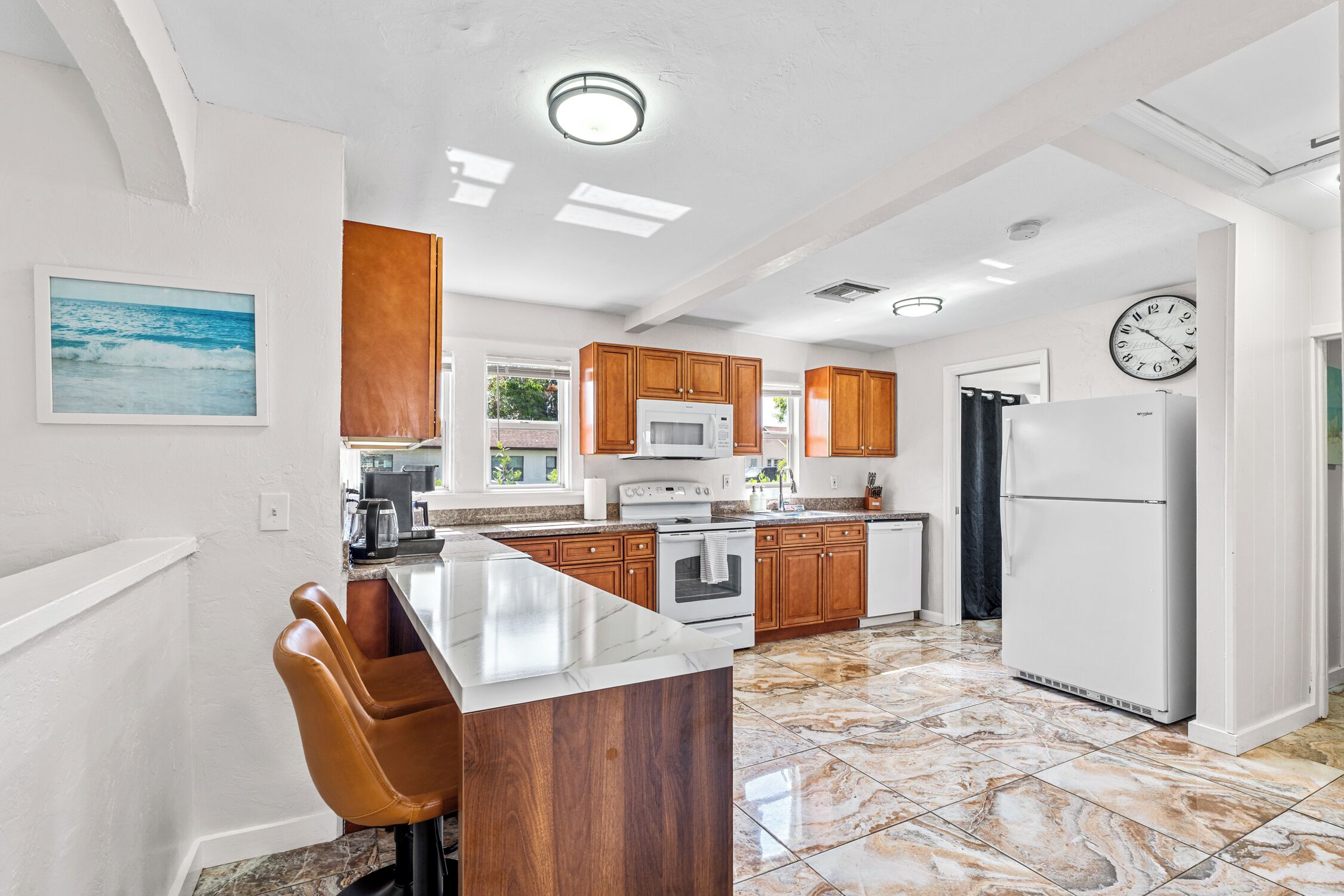 A modern kitchen with wooden cabinets, a marble countertop, and a built-in oven.