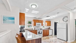 A modern kitchen with wooden cabinets, a marble countertop, and a built-in oven. - NEW: Cozy Home w/ Hot tub & Beach Essentials! (Lake Worth Beach)