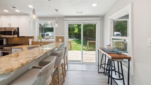 Een moderne keuken met een groot keukenblok, barstoelen en een schuifdeur naar een terras.