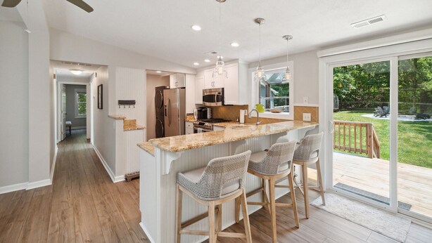 Een moderne keuken met een centraal eiland, barkrukken en uitzicht op de omgeving.