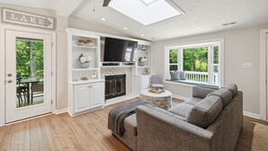 Een moderne woonkamer met een open haard, een plafondventilator en uitzicht op de omgeving.