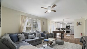 A modern living room with a sectional sofa, ottoman, and a dining table.