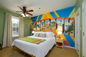 A bedroom with a bed, a ceiling fan, a window with curtains, a nightstand with a lamp, and a colorful mural on the wall. - Stylish Retreat Close to Dining and Outlets, Minutes to Beach (Rehoboth Beach)