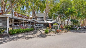 A restaurant with outdoor seating, a sign for 'RATTLE HUM BAR GRILL,' and a sign for 'THE BEER from UP HERE.' - Relaxing Beachfront Palm Cove Studio with Ocean Views, Pool Access & Walkable Dining (Palm Cove)
