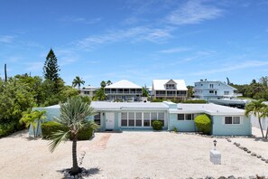 A coastal property with a light blue building, a white building with a gabled roof, and a large white house with multiple stories. - Port Palermo - Canal Home w/Dockage, Pet Friendly! (Islamorada)