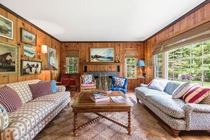 Ein gemütliches Wohnzimmer mit Holzwänden, einem Kamin, zwei Sofas und einem Couchtisch.