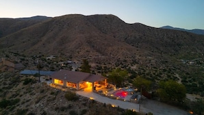 A single-story building with a patio area, surrounded by a desert landscape with hills in the background. - Casa Sole | Pool | Spa | Near Palm Springs (Morongo Valley)