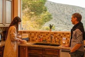 A kitchen with a checkered backsplash, a sink, and a window overlooking a mountainous landscape.