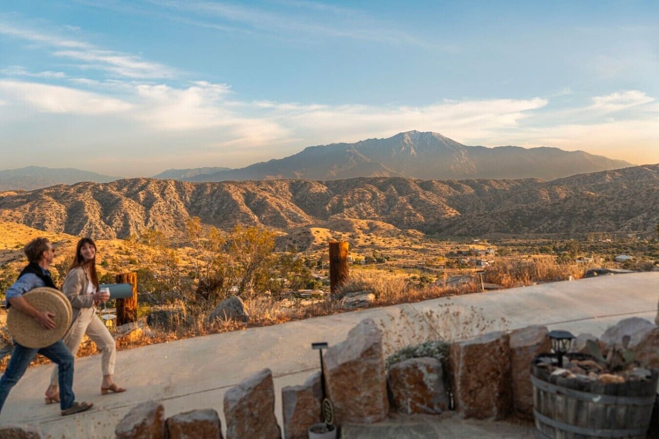 Un couple se promène sur un sentier pavé de pierres, avec une vue sur les montagnes et un paysage rural.