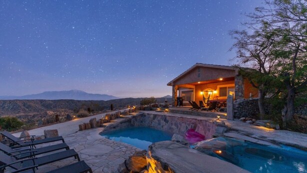 A pool area with stone flooring, lounge chairs, and a fire feature. - Casa Sole | Pool | Spa | Near Palm Springs (Morongo Valley)