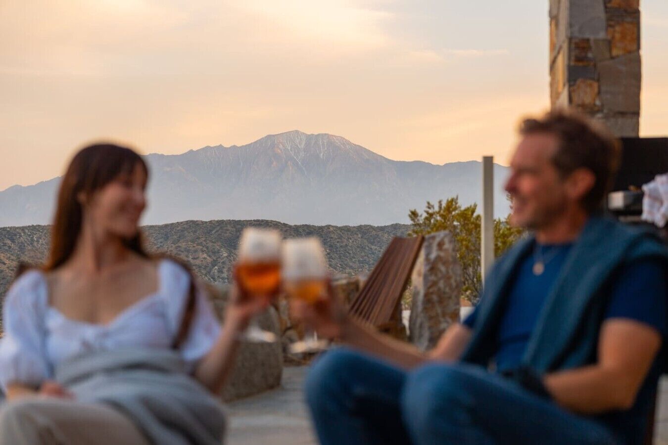 Two people sitting outdoors with a mountain in the background.