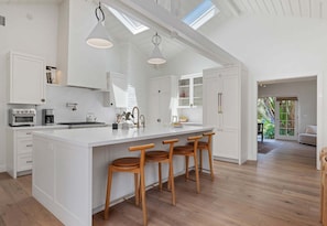 A spacious kitchen with a large island, wooden bar stools, white cabinetry, and skylights. - NEW Montecito Hedgerow Jewel Box, 4BD/3BA, with Pool and Jacuzzi! (Santa Barbara)