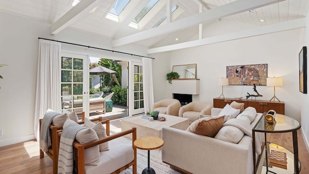Un salon spacieux avec un plafond haut, de grandes fenêtres, une cheminée et une vue sur l’extérieur.