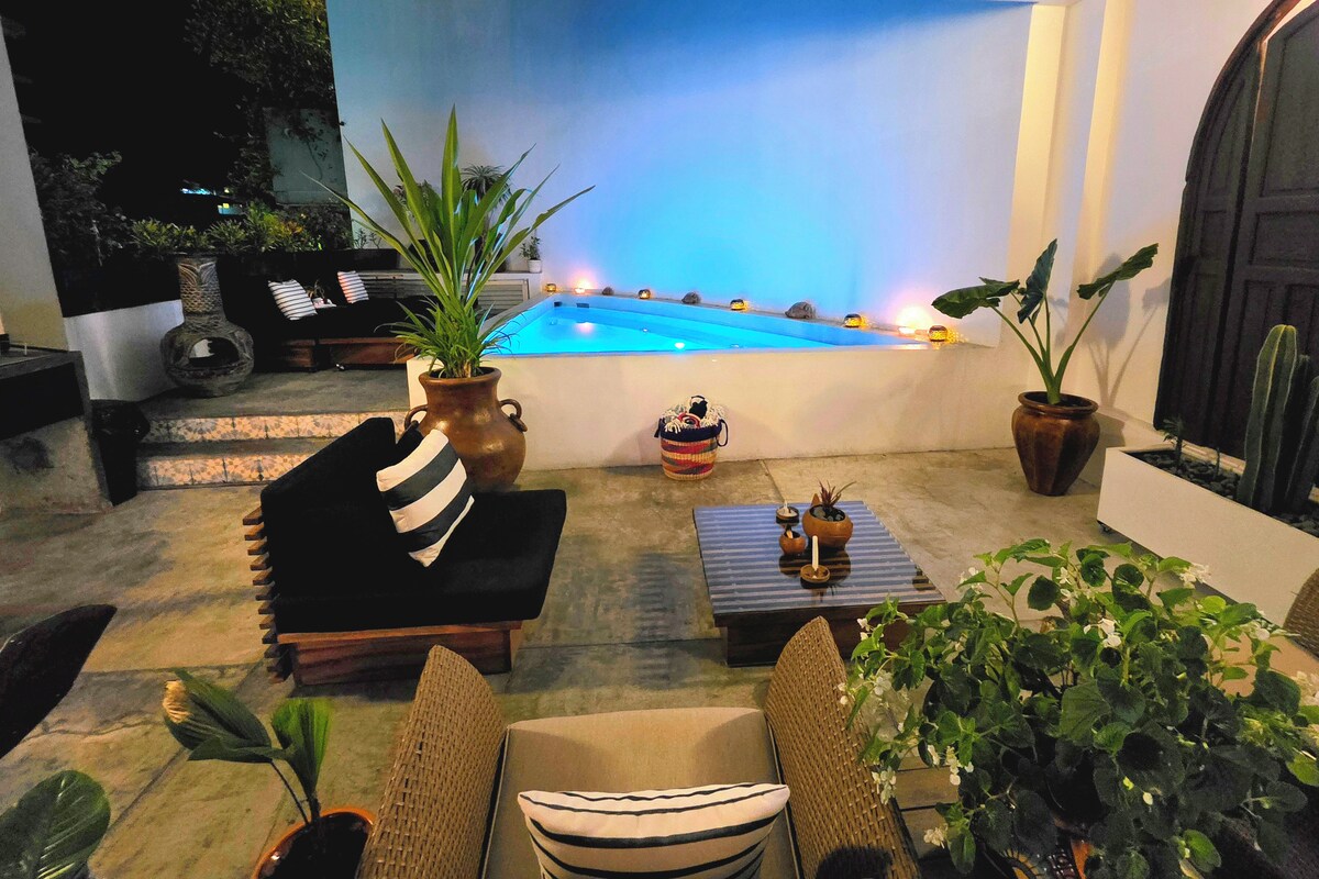 An outdoor seating area with a pool, potted plants, and a door.