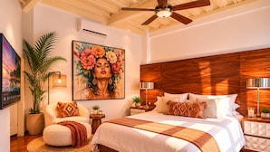 A bedroom with a wooden headboard, a large bed with white bedding, a ceiling fan, a potted plant, and a painting on the wall. - Ava 19 Adults Only Villa - Bed & Breakfast (Puerto Vallarta)