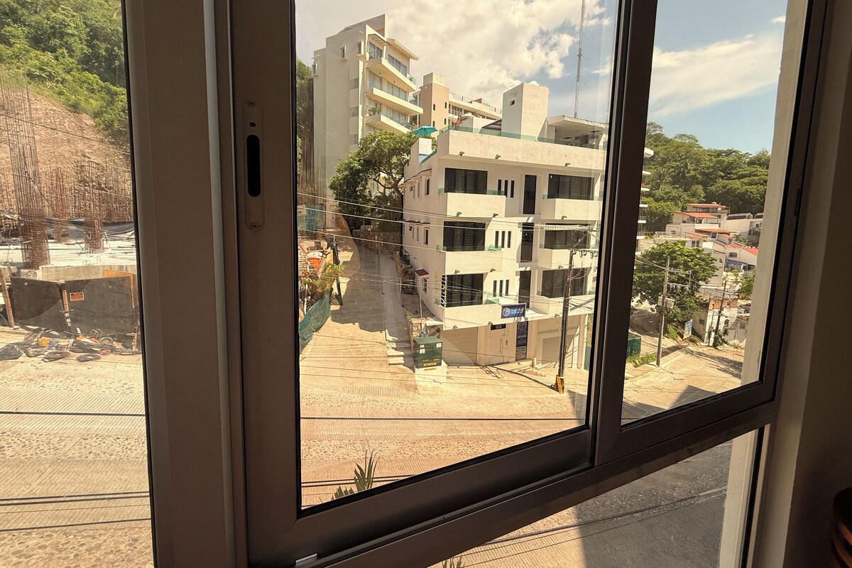 A view through a window of a building with multiple floors, construction materials, and a construction site visible outside.