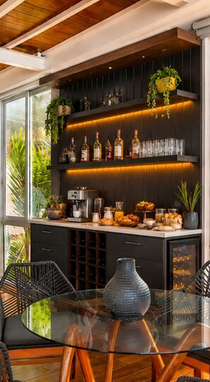 Een moderne keuken met een glazen eettafel, donkere kastjes en een koffieapparaat.