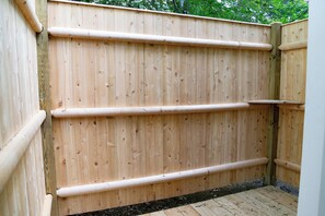 A wooden fence with horizontal bars, a wooden deck, and a small garden area. - Charming Cape with AC near downtown Falmouth (Falmouth)