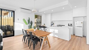 Una cocina moderna con armarios blancos, una mesa de comedor de madera y sillas negras.
