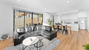 Una sala de estar moderna con un sofá seccional, una mesa de comedor y una zona de cocina.