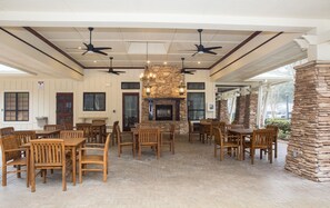 A spacious indoor area with multiple wooden tables and chairs, a stone fireplace, and ceiling fans. - Recently updated Private resort style condo  (St. Augustine)