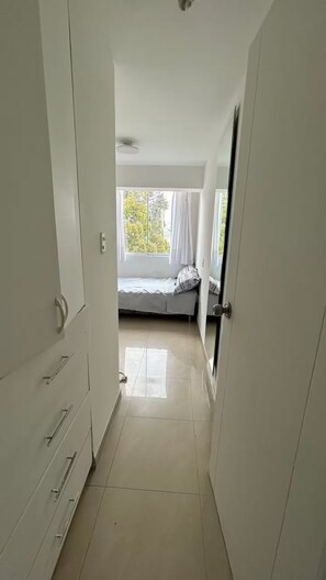 Ein Korridor, der zu einem Schlafzimmer mit Bett, Fenster und Tür führt.