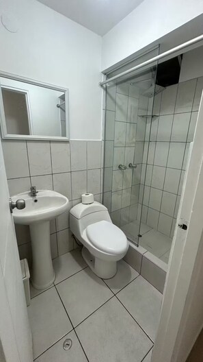 Un bagno con lavabo, wc e box doccia in vetro.