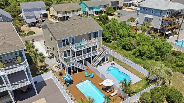 Ein Wohngebiet mit zwei Schwimmbecken, einem großen Haus mit Terrasse und einem kleineren Haus mit Balkon.